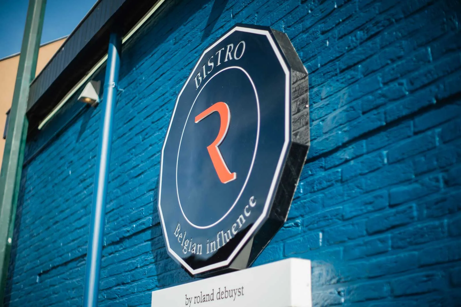 Het achthoekige Bistro R-logo op de blauwe bakstenen gevel
