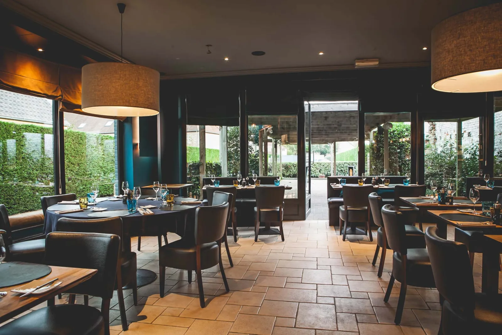 Eetzaal met tafels langs de ramen en een tegelvloer