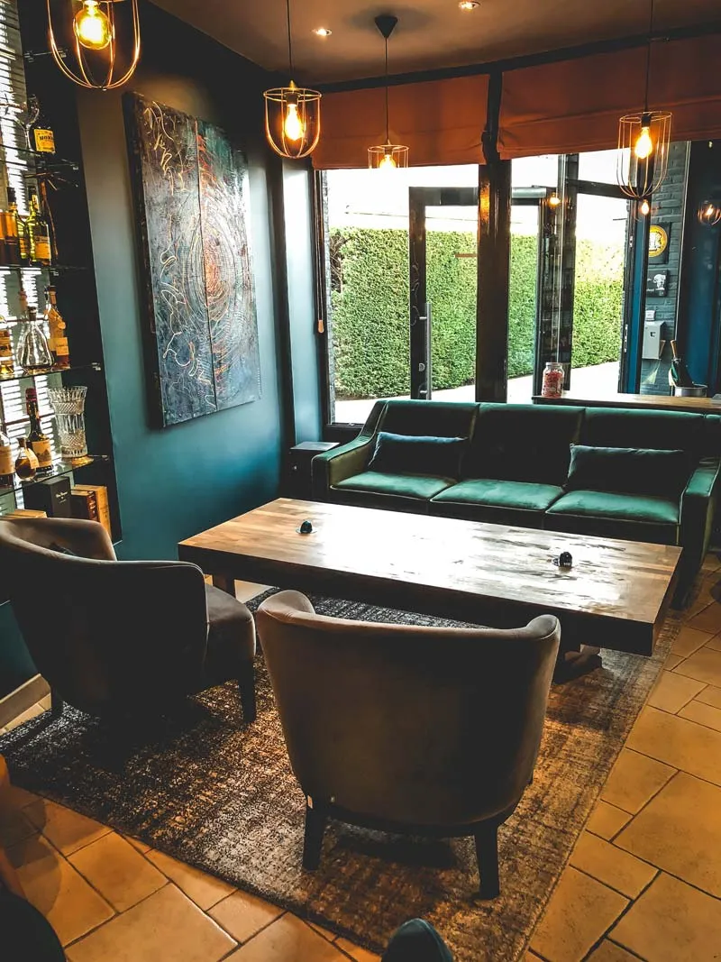 Houten tafel met leren fauteuils bij het raam, met kunstwerk aan de muur